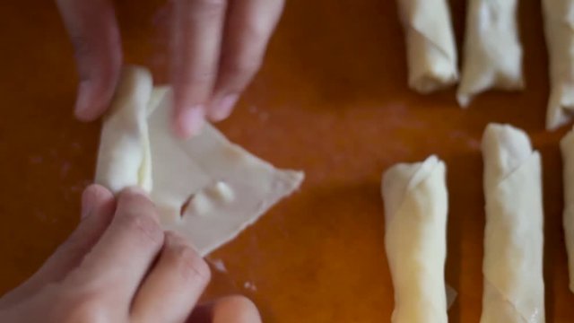 Overhead of lumpia being filled and rolled.
