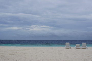 Empty loungers on the beach in the Maldives on a cloudy day