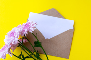 Love envelope with blank letter and pink chrysanthemum flowers on bright yellow bacground. Copy space