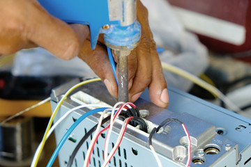 Technician is soldering the car stereo unit