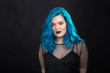 Style and fashion concept - Young and attractive woman with blue hair posing over black background