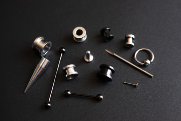 Diverse set for piercing on a dark background, ear tunnels, tunnels and earrings for the ears and...