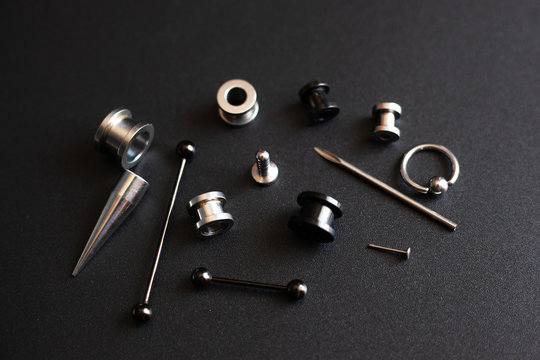 Diverse set for piercing on a dark background, ear tunnels, tunnels and earrings for the ears and tongue close-up
