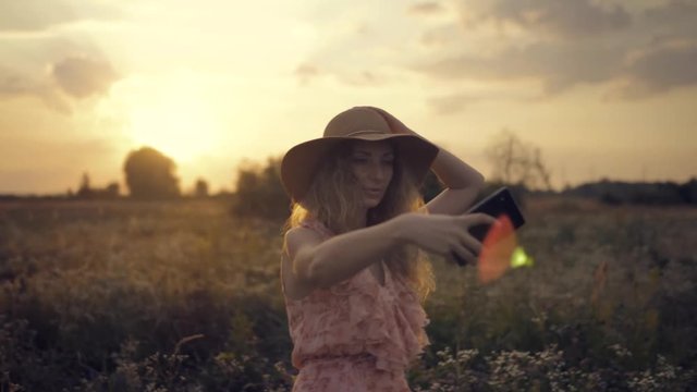 Beautiful Woman Enjoing Nature At Sunset.Woman In Hat Takes Selfie At Sunrise.Selfie At Sunrise.Blonde Woman Taking Selfie At Sunset In Field.Girl Taking Photo And Smailing.Woman Portrait At Sunset.