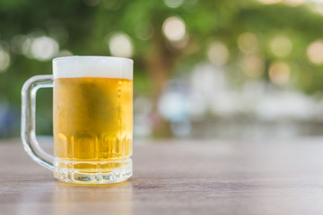Beer in glass on wooden table with natural background with bokeh