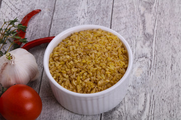 Raw bulgur in the bowl with tomatoes and garlic