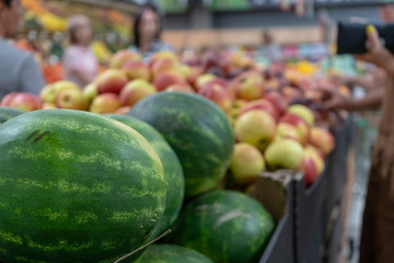 Close-up of fresh, ripe green watermelons on the store counter in front of fruits