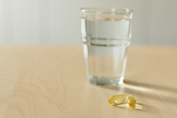 Fish oil capsules and glass of water on the table. Cod liver oil, omega-3. Nutritional supplements. Sport,diet concept.