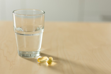 Fish oil capsules and glass of water on the table. Cod liver oil, omega-3. Nutritional supplements. Sport,diet concept.