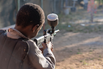 Young boy shooting target range with paintball gun