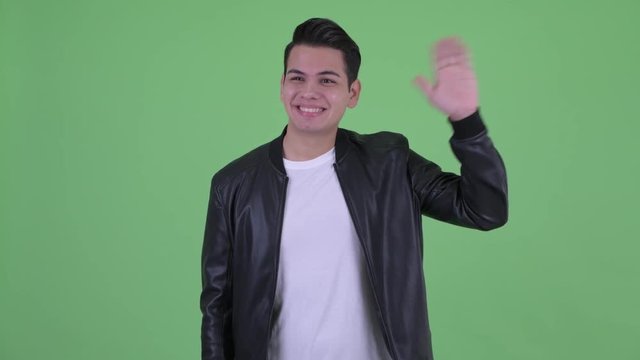 Happy young multi ethnic man with leather jacket waving hand