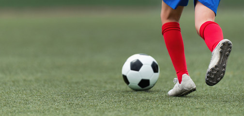 Foot of a child football player and ball on the football field