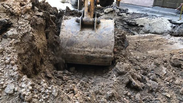 Excavator bucket pours ground. Repair work plumbing.