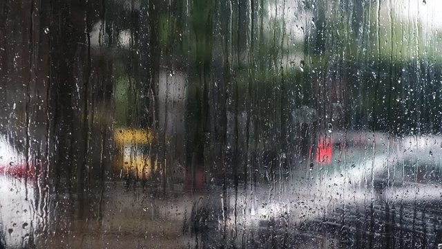 Abstract traffic in raining day. Road view through car window with rain drops. Blurred background.