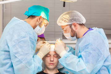 Obraz na płótnie Canvas Baldness treatment. Hair transplant. Surgeons in the operating room carry out hair transplant surgery. Surgical technique that moves hair follicles from a part of the head.