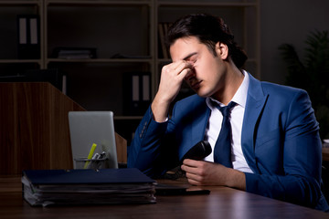 Young male employee working night in the office 