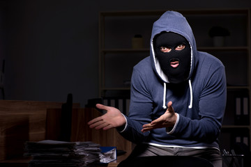 Male thief in balaclava in the office night time 