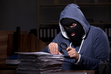 Male thief in balaclava in the office night time 