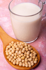 In the foreground, a glass with soy milk and soy beans in the wooden spoon