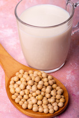 In the foreground, a glass with soy milk and soy beans in the wooden spoon