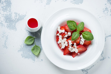 White plate with summer dessert made of fresh strawberries, flatlay over white concrete background, horizontal shot