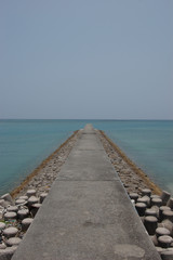 Fototapeta na wymiar 南国沖縄のエメラルドグリーンの海の防波堤