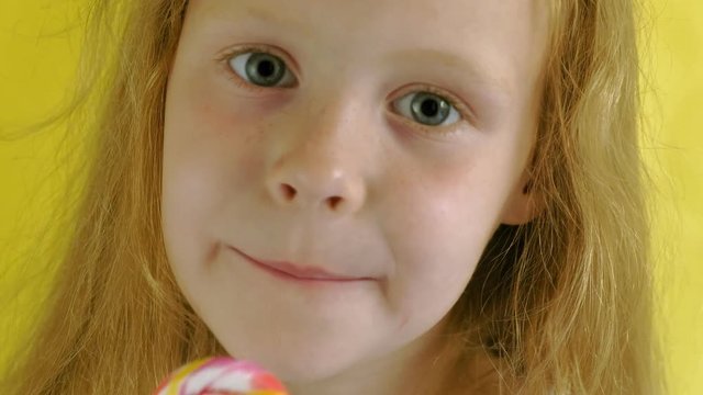 Little girl with a lollipop on a Yellow background. Close up portrait