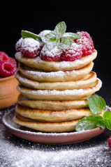 Pancakes with raspberries and berries around on black backgound