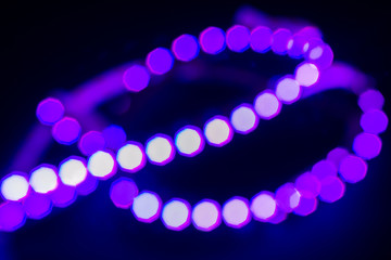 Violet neon bokeh lights curl on black. Abstract background for your design