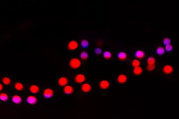 Duotone red and purple neon bokeh lights on black. Festive concept