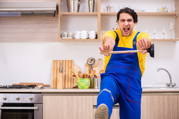 Young male contractor repairing tap at home 
