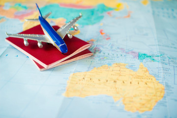 toy aircraft and two neutral passports on the world map. travel and air transportation concept, flight to australia, trip by plane, booking flights