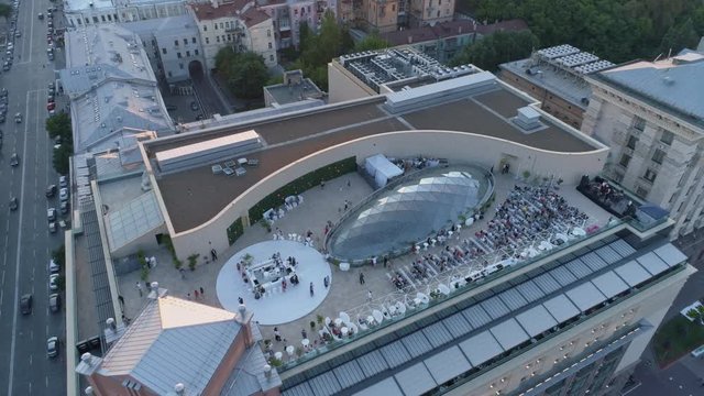 Aerial view. People are listening a music at open air roof concert hall. 4K