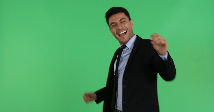 Portrait close up scene video of happy Caucasian businessman in black suite moving his body and dancing isolated on green background.