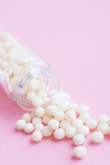 homeopathic globules and glass bottle close up on pink background. Alternative Homeopathy medicine herbs, healtcare and pills concept. Flatlay. Top view. copyspace for text