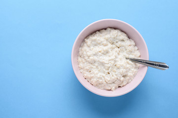 Top view of pink clay plate with oatmeal on blue background, copy of space