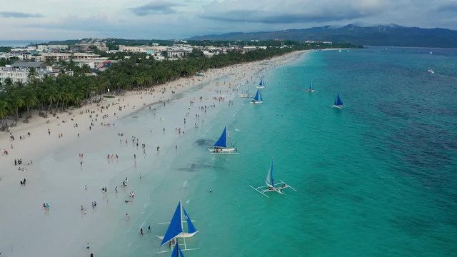 Aerial view of crowds of people on a tropical sandy beach to watch sunset (Boracay, Philippines)