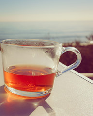 Mug with tea drink on ocean beach background