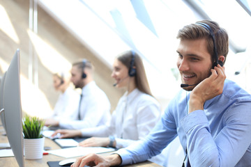 Portrait of call center worker accompanied by his team. Smiling customer support operator at work.