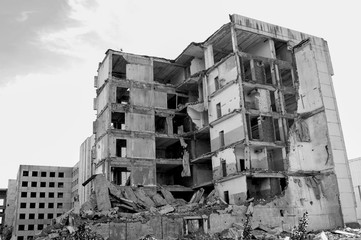 The remains of a destroyed concrete building against the sky. Black and white. Background