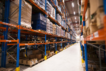 Interior of large distribution warehouse. Shelves stacked with palettes and goods ready for the market.