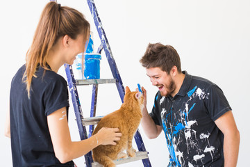 People, redecoration and renovation concept - portrait of couple with cat pour paint