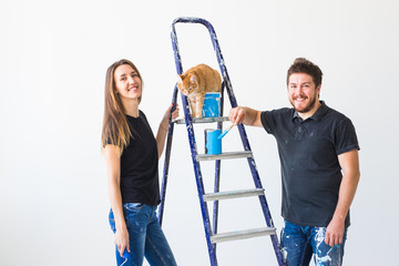 Repair, renovation, pet and love couple concept - young family with cat doing repair and painting walls together and laughing