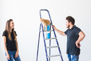 People, renovation, pet and repair concept - Portrait of funny man and woman with cat doing redecoration in apartment