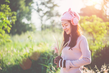 Cute woman standing on the background of flowers with soft sunlight, Her stands in white pink dress with her eyes closed and a small smile smiling tende.