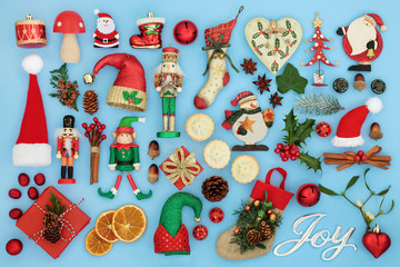 Symbols of Christmas with silver joy sign, retro bauble tree decorations, flora and food selection on pastel blue background Traditional symbols for the festive season.