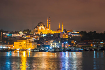 Night view of Istanbul cityscape Suleymaniye Mosque (Rustem Pasha Mosque) with floating tourist boats in Bosphorus ,Istanbul Turkey