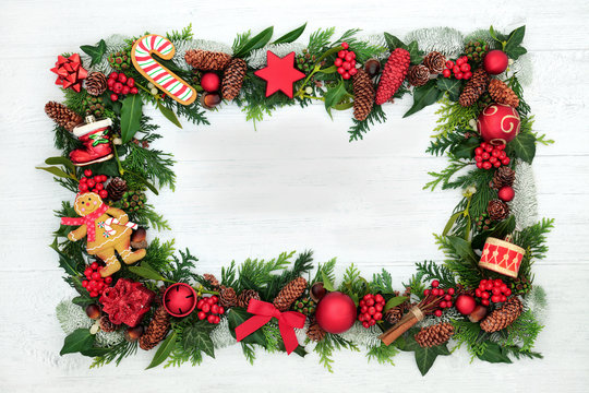 Christmas decorative background border with festive baubles, holly and winter flora on rustic white background with copy space.
