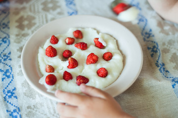White bowl of Semolina porridge with strawberries on wooden table