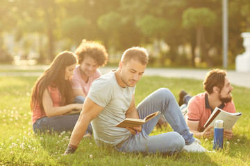 A group of students studying books sitting in a city park.